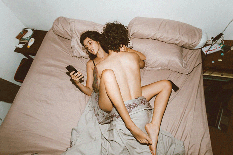 woman looking at phone during sex
