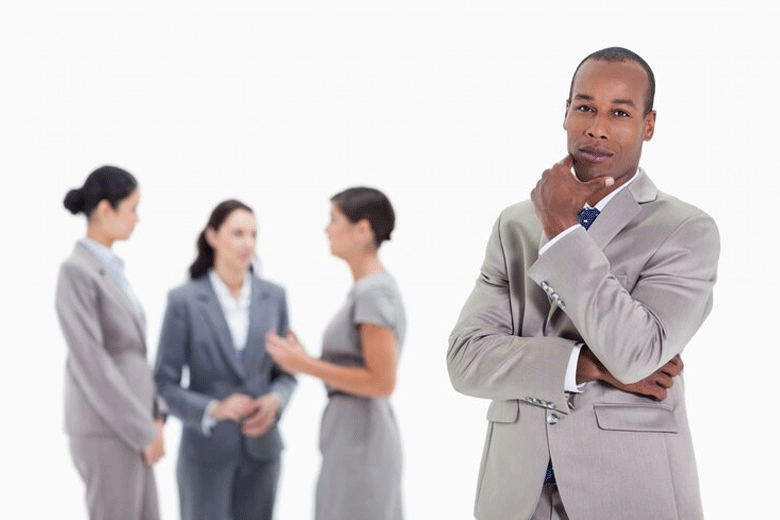 A man stands aside from ladies in an office